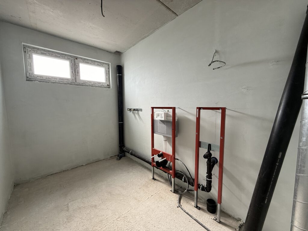 Badezimmer im Neubauprojekt Bad Oeynhausen mit vorbereiteten Sanitäranschlüssen und Fenster während der Bauphase.