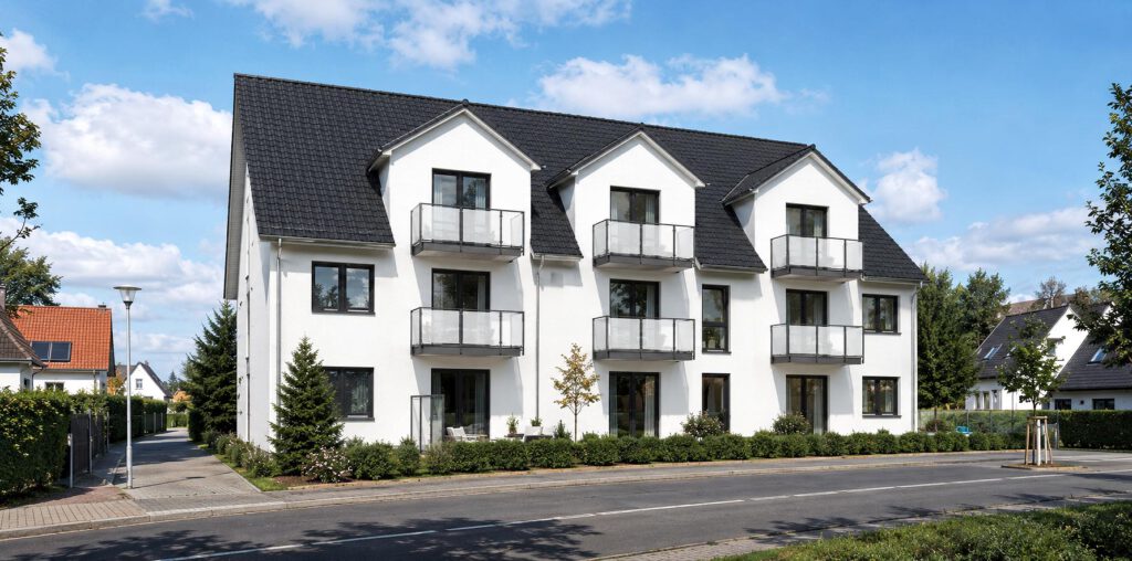 Fertiggestelltes Mehrfamilienhaus in Bad Oeynhausen – dreigeschossiger Massivbau mit weißer Putzfassade, Satteldach und Balkonen mit Glasgeländern, realisiert als gefördertes Wohnprojekt mit KfW-55-Standard.